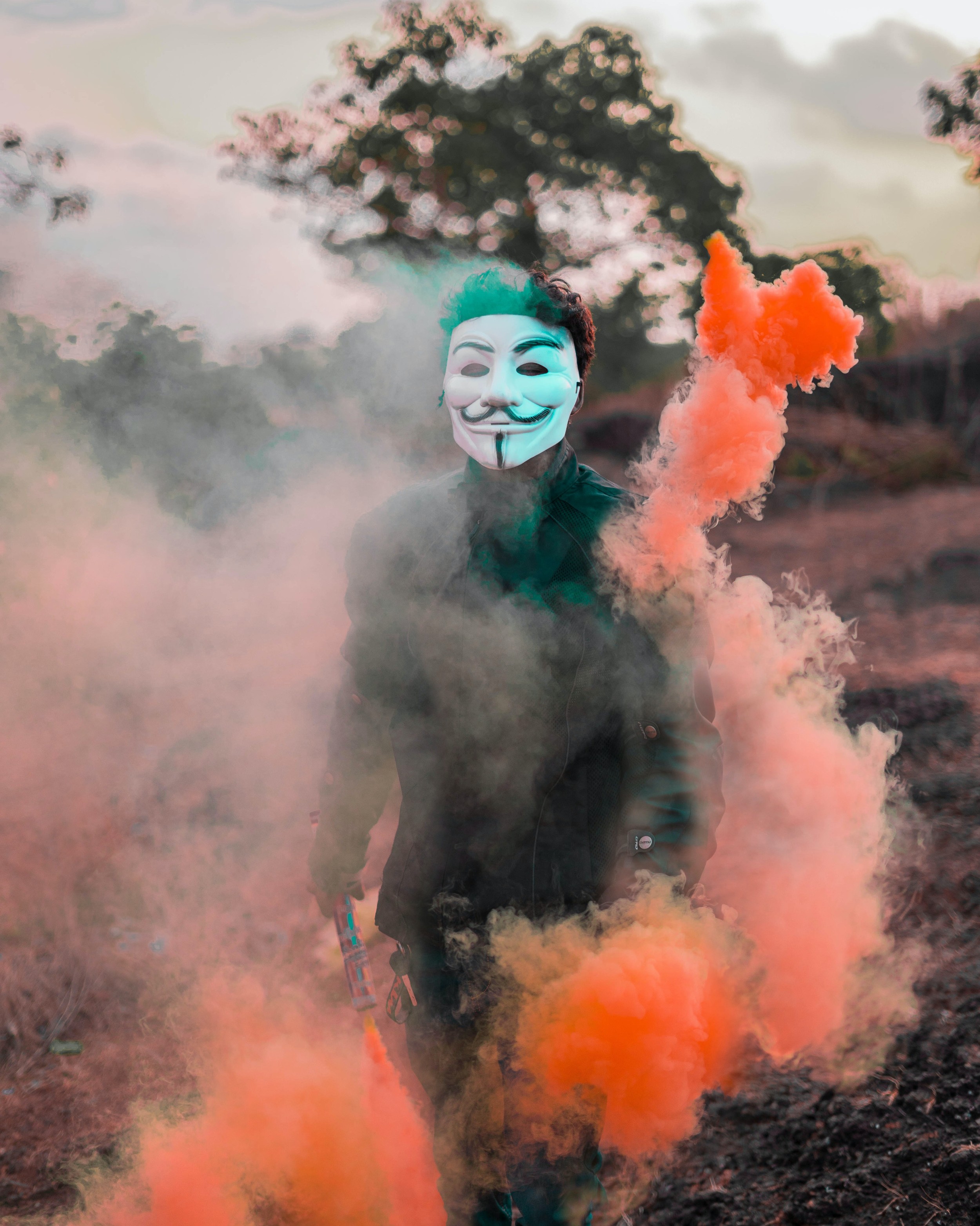 Foto von Asif pav: https://www.pexels.com/de-de/foto/person-die-guy-fawkes-maske-tragt-die-mit-farbigem-rauch-umgeben-ist-3093526/