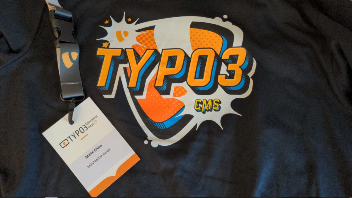 Schwarzes T-Shirt mit TYPO3 CMS Logo und dazugehörigem Konferenz-Ausweis der TYPO3 Developer Days 22 für Malte Müns von MÜNSMEDIA GmbH